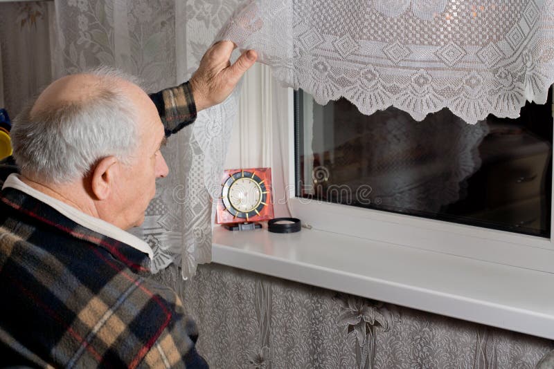 Elderly man peering out through the window