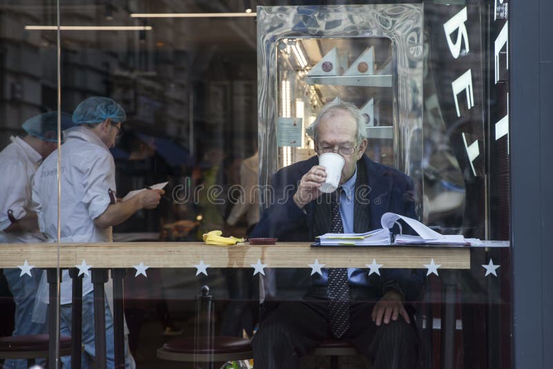 Elderly man reading a newspaper for morning coffee in a shop window stock photos Elderly man reading a newspaper for morning coffee in a shop window stock photos