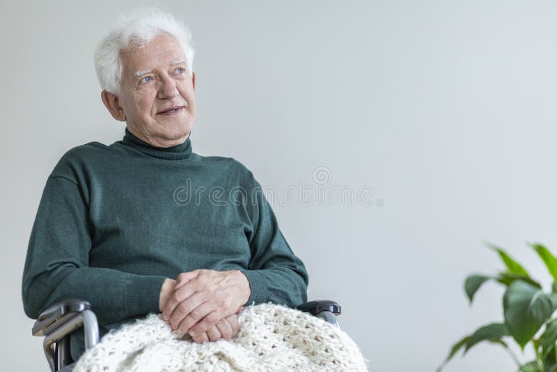 Elderly men sitting in a wheelchair and thinking about good times. Place your poster concept