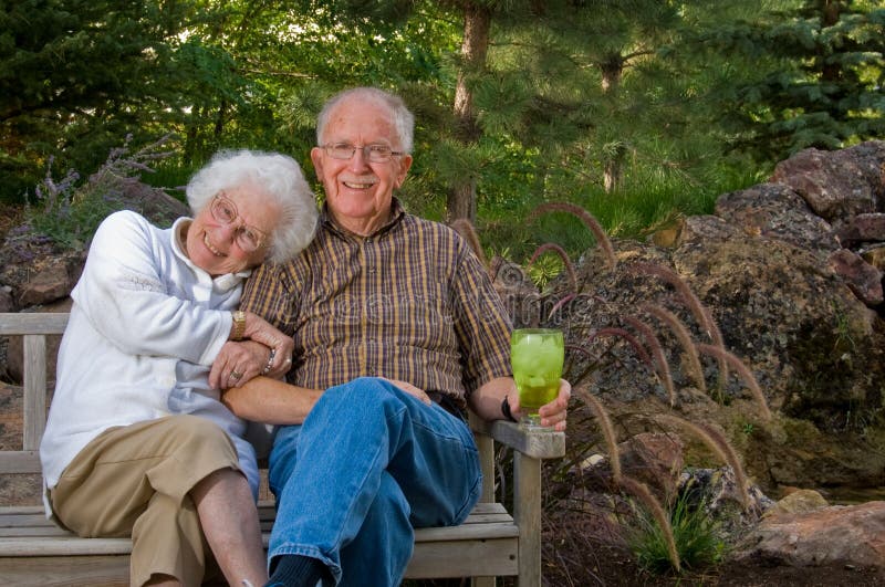 Senior man and woman sitting on a bench by a man-made pond and waterfall. Man made waterfall stock images, royalty-free photos and pictures