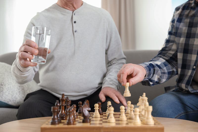 Elderly men playing chess at nursing home, closeup. Assisting senior stock photo Elderly men playing chess at nursing home, closeup. Assisting senior stock photo