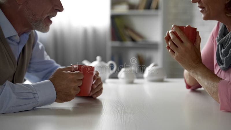 Elderly man and woman sitting at kitchen table, drinking tea, happy couple royalty free stock image Elderly man and woman sitting at kitchen table, drinking tea, happy couple royalty free stock image