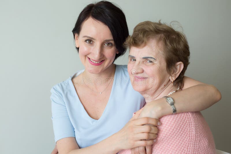 Elderly mother with adult daughter hugging portrait stock images.