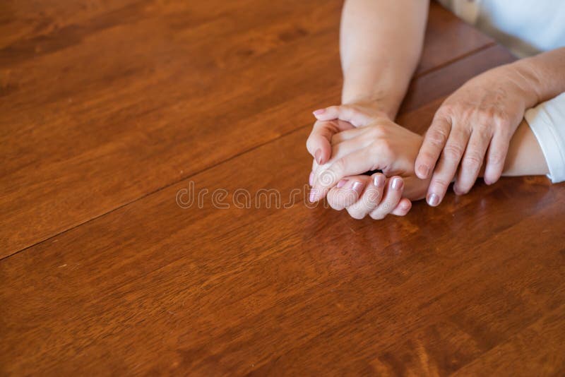 Elderly Mother And Her Daughter Holding Hands While Sitting At The
