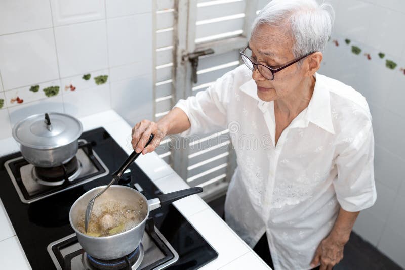 Elderly people cooking vegetables soup or stock in a saucepan and heating the ingredients,healthy food,good cook,asian senior