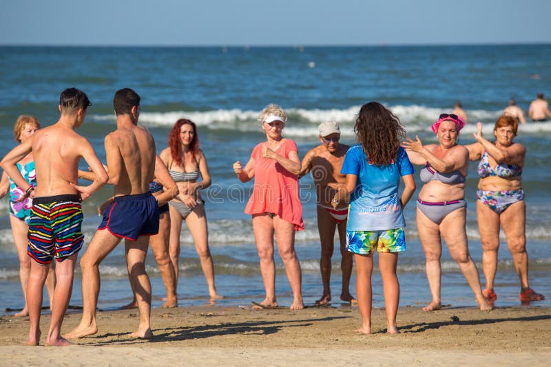 Elderly people doing wellness exercises on the beach stock photo Elderly people doing wellness exercises on the beach stock photo
