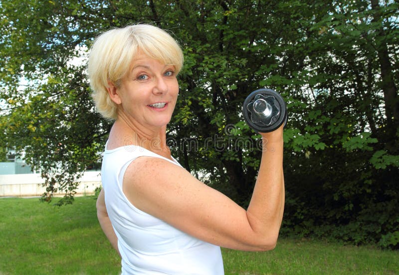 Elderly woman doing outdoor training in a park with dumbbell royalty free stock photos Elderly woman doing outdoor training in a park with dumbbell royalty free stock photos