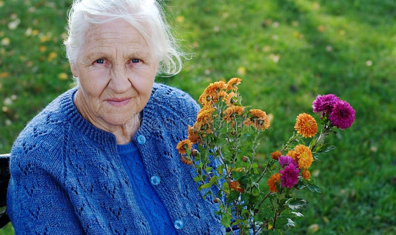 Más viejo una mujer sobre el prado verde, sobre el otono estación.