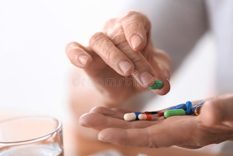 Elderly woman holding different pills, closeup