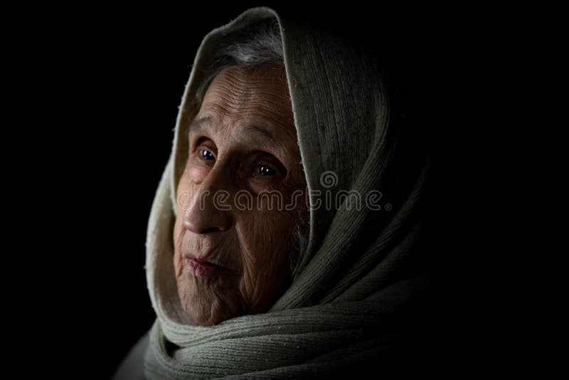 Elderly woman with scarf on black background, studio portrait