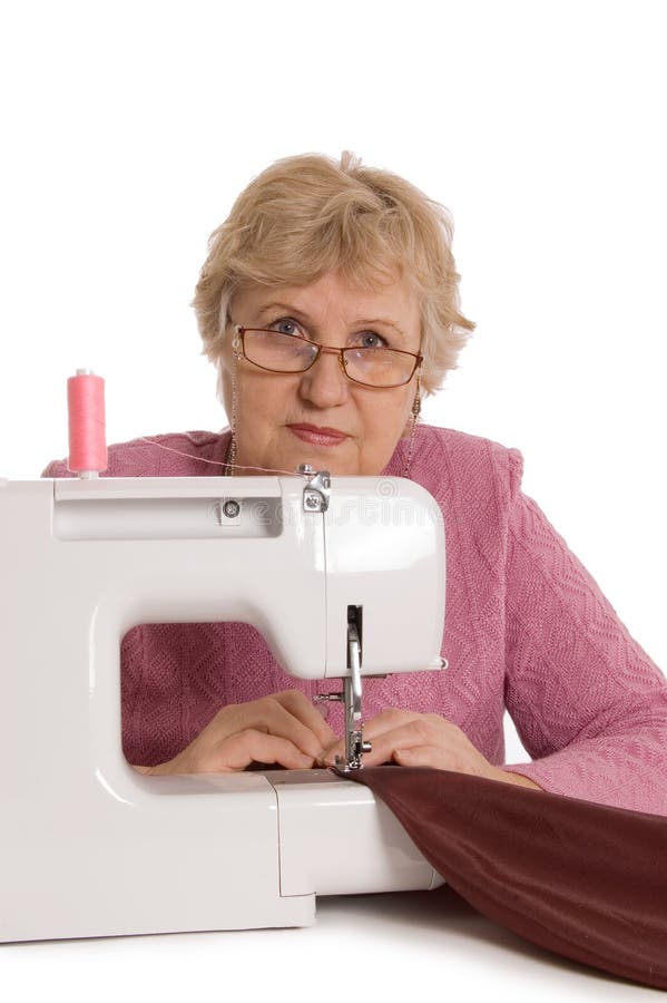 The elderly woman sews on the sewing machine