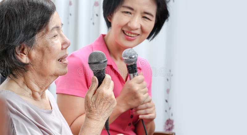 Elderly women happiness sing a song on microphone at home. Elderly women happiness sing a song on microphone at home.