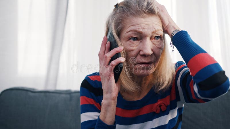 Elderly woman using smartphone to make phone call. Receiving bad news