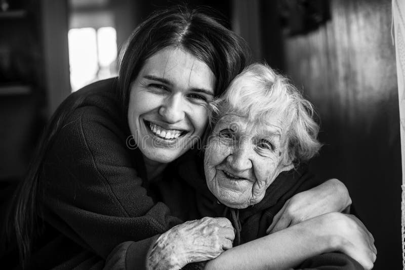 Elderly woman in an embrace with his adult daughter. 