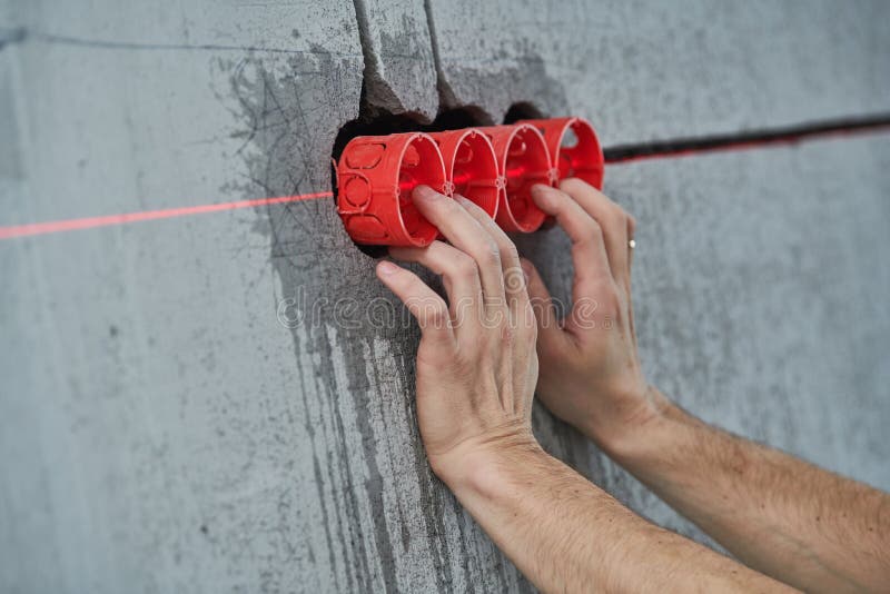 Elecrician work. Installing wall electric outlet with laser level royalty free stock image Elecrician work. Installing wall electric outlet with laser level royalty free stock image