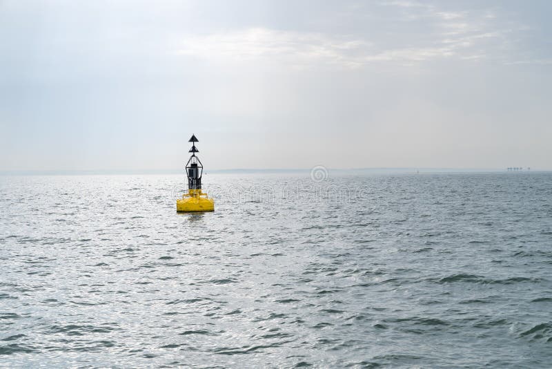 Electric bollard light or buoy on the open sea in the esuary of the Thames, England, UK with the Red Sands Maunsell Forts in the