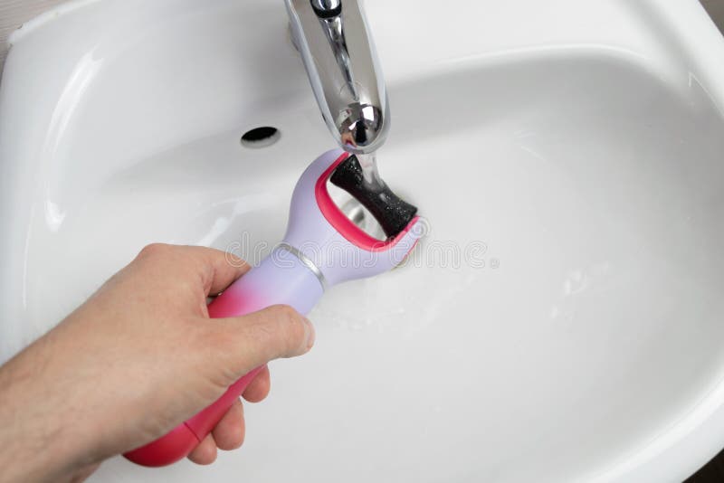 The main subject is out of focus, electric callus remover machine white background closeup remove old skin care treatment male hand hold bathroom sink. The main subject is out of focus, electric callus remover machine white background closeup remove old skin care treatment male hand hold bathroom sink