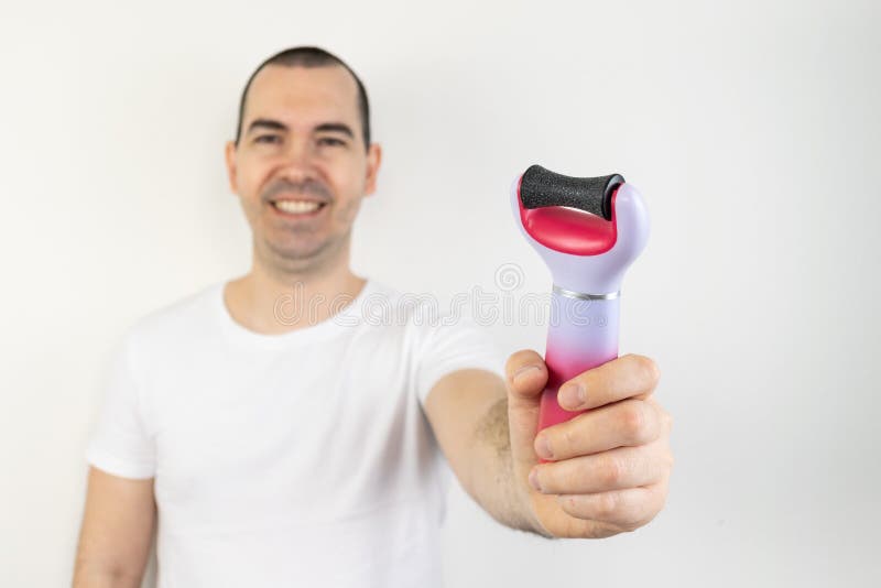 The main subject is out of focus, electric callus remover machine white background closeup remove old skin care treatment male hand hold happy smile. The main subject is out of focus, electric callus remover machine white background closeup remove old skin care treatment male hand hold happy smile