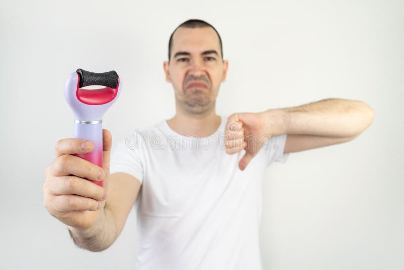 The main subject is out of focus, electric callus remover machine white background closeup remove old skin care treatment male hand hold happy smile thumbs down unhappy. The main subject is out of focus, electric callus remover machine white background closeup remove old skin care treatment male hand hold happy smile thumbs down unhappy