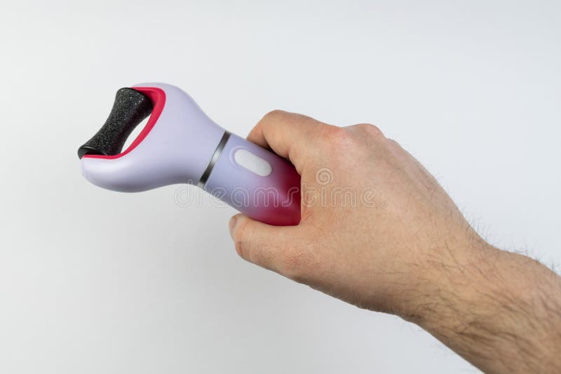 The main subject is out of focus, electric callus remover machine white background closeup remove old skin care treatment, male man hand hold