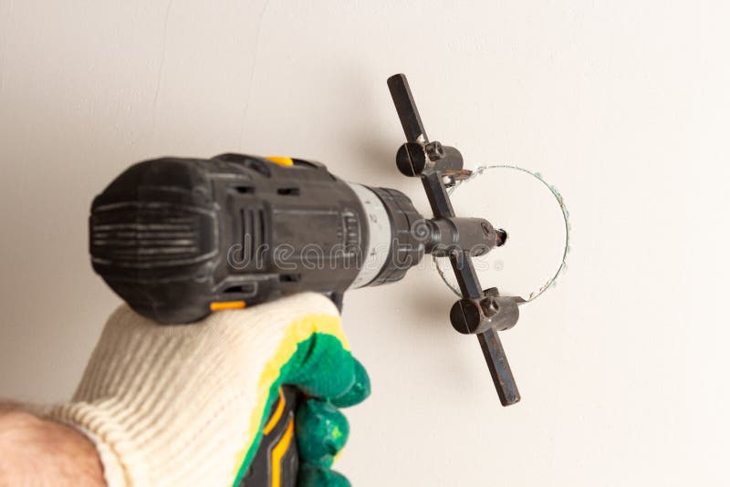 An Electric Drill with a Drill Drills Holes in Drywall. Closeup Stock