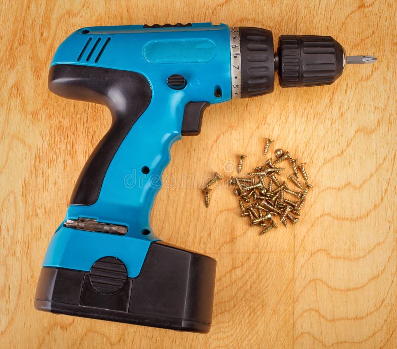 Cordless Drill and Large Screws on a Wood Background Stock Image