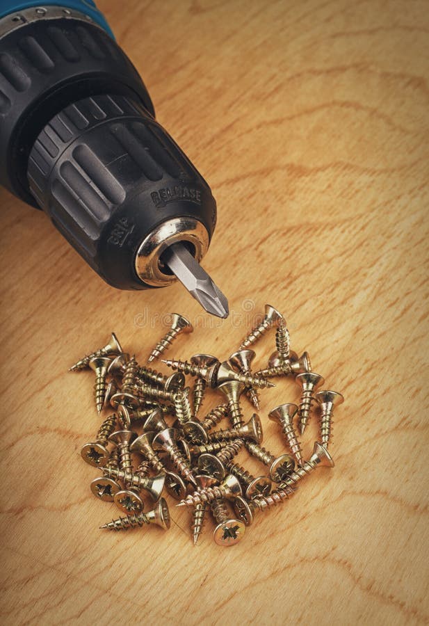 Cordless Drill and Large Screws on a Wood Background Stock Image