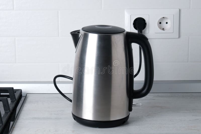 White electric kettle stands on a gray table plugged into a power outlet  Stock Photo - Alamy