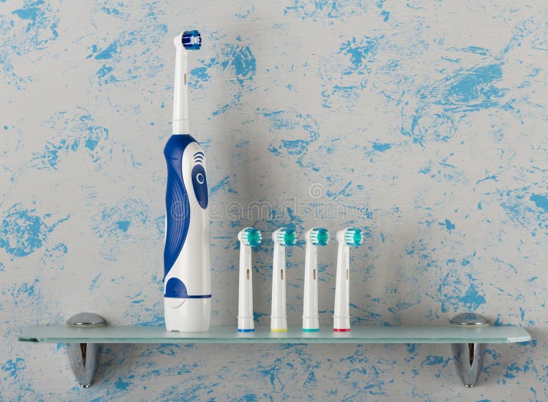 Electric toothbrush with extra nozzles of different colors on glass shelf