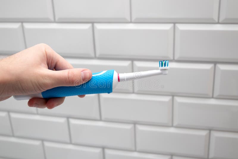 Electric Toothbrush in Hand. daily Routine in the Bathroom Stock Photo