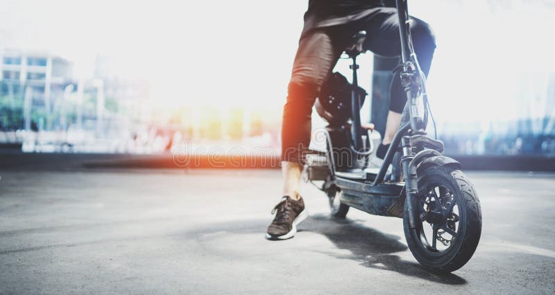 Electric urban transportation.Young man ready to ride his electric scooter bike in the center of a city. Wide royalty free stock image Electric urban transportation.Young man ready to ride his electric scooter bike in the center of a city. Wide royalty free stock image