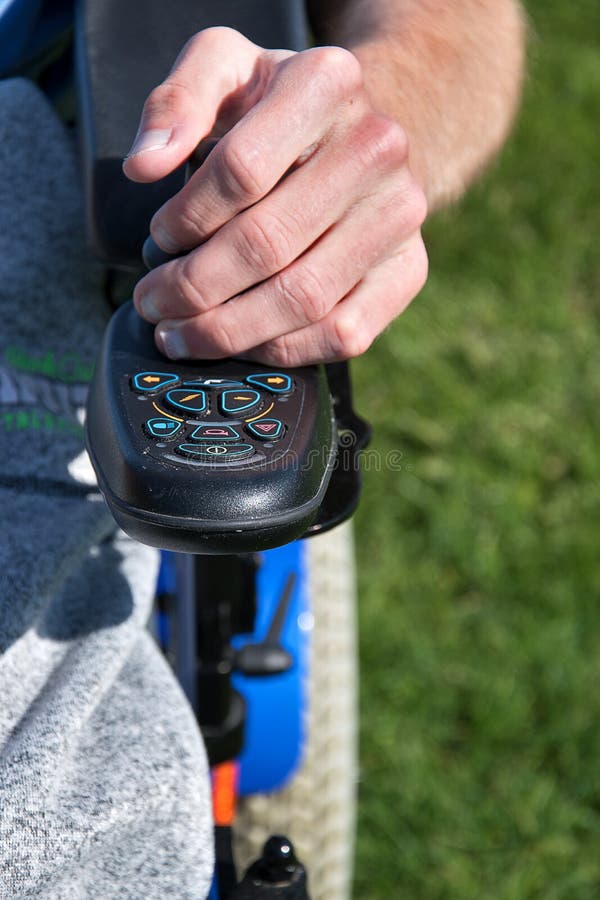 Electric Wheelchair. Young Man Controls a Wheelchair with His Left Hand