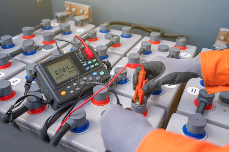 Electrical and instrument technician measuring voltage and internal resistance of battery.