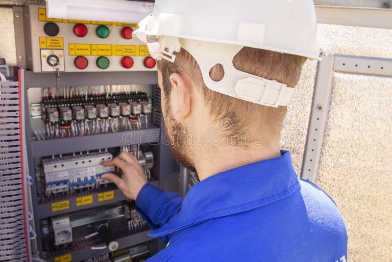 The electrician adjusts the electrical cabinet. engineer in helmet is testing electrical equipment stock photo