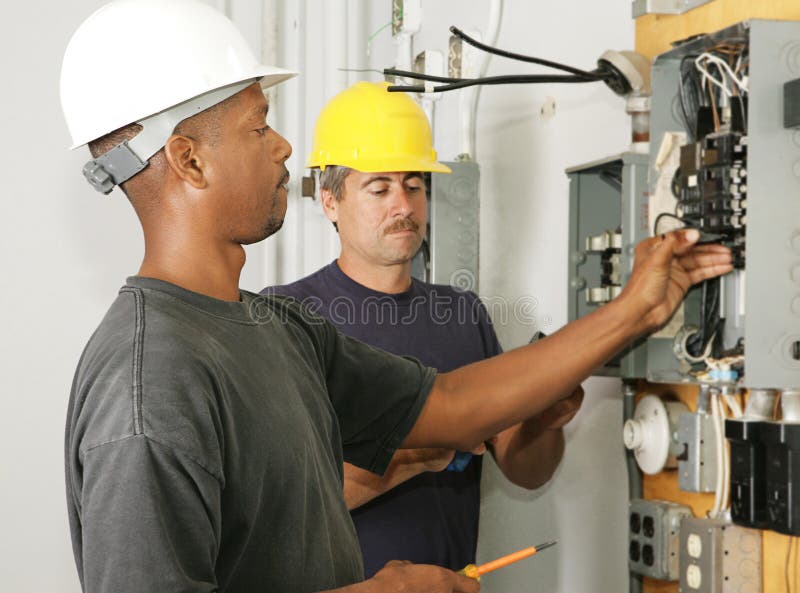 Africký američan a kaukazských elektrikár pracuje na panel.