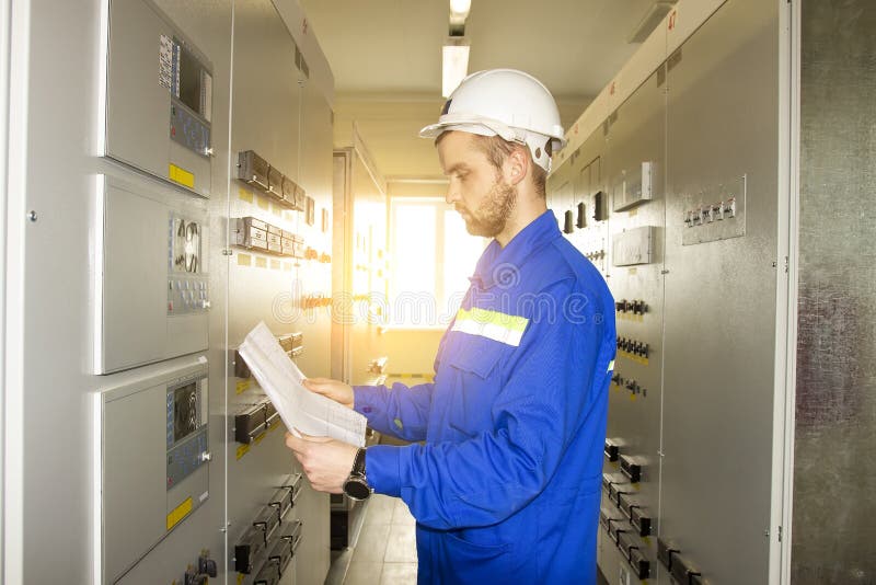 Electrician Engineer on control panel with electric scheme. Maintenance of electrical equipments stock photos