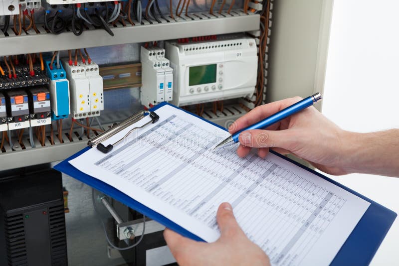 Electrician holding clipboard while examining fusebox