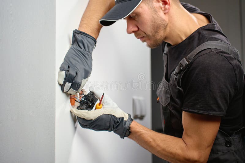 Electrician installing electrical wall switch and connecting wires inside wall using screwdriver. Concept of professional electrical work, home renovation and safe installation. Home electrician stock images, royalty-free photos and pictures