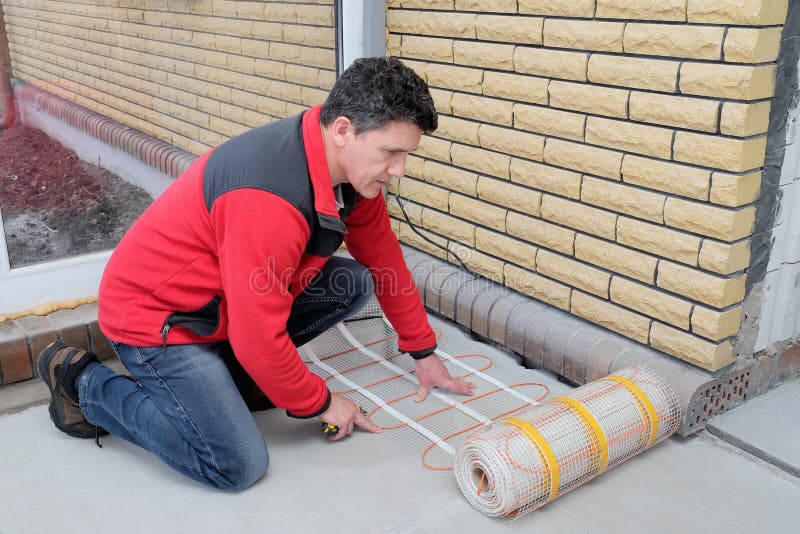 Electrician Installing Heating Electrical Cable on Concrete Floor. Man