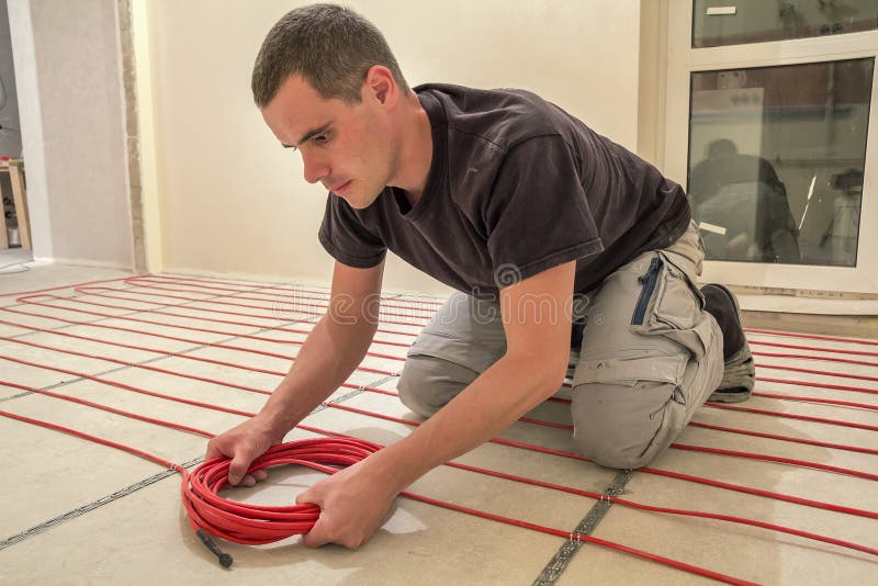 Electrician Installing Heating Red Electrical Cable Wire on Cement
