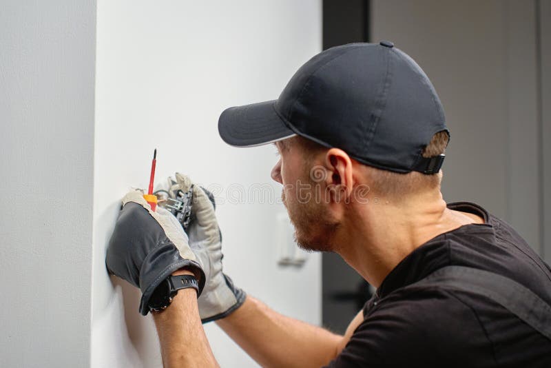 Electrician installing electrical wall switch and connecting wires inside wall using screwdriver. Concept of professional electrical work, home renovation and safe installation. Home electrician stock images, royalty-free photos and pictures