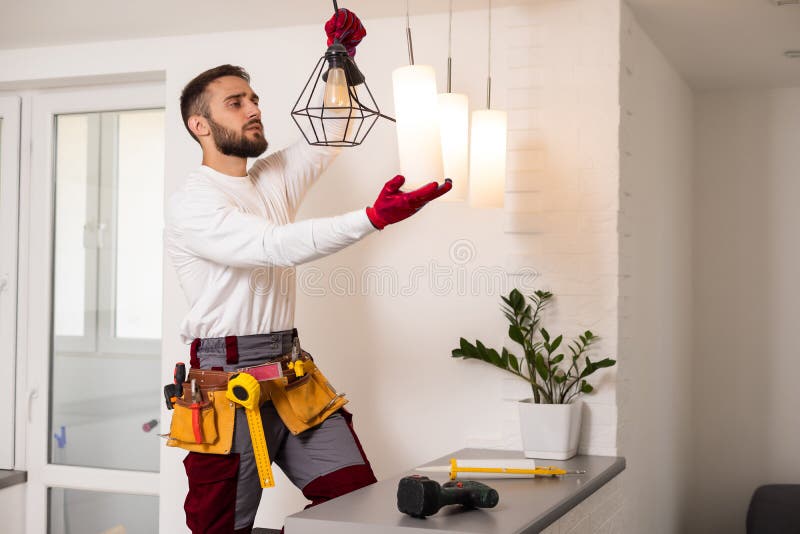 Electrician installs lamp lighting and spot loft style on ceiling. stock images