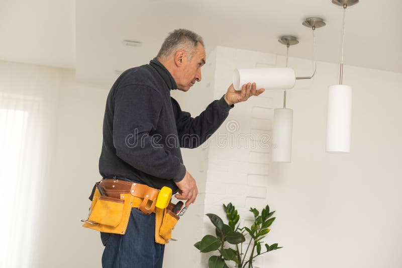 Electrician installs lamp lighting and spot loft style on ceiling royalty free stock photography