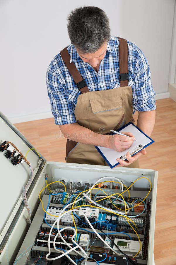 Electrician looking at fuse box stock photography