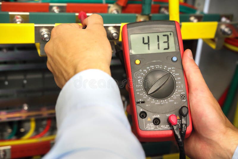 Electrician measures voltage in fuse box. Engineer with electrical tools examining electrical cabinet. royalty free stock photos