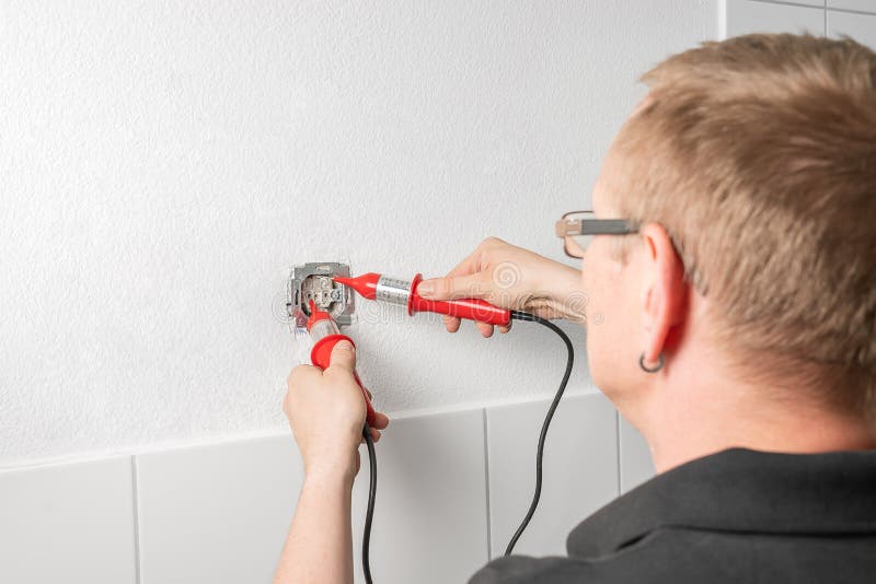 An electrician measures the voltage at a power outlet with a voltage indicator stock images An electrician measures the voltage at a power outlet with a voltage indicator stock images