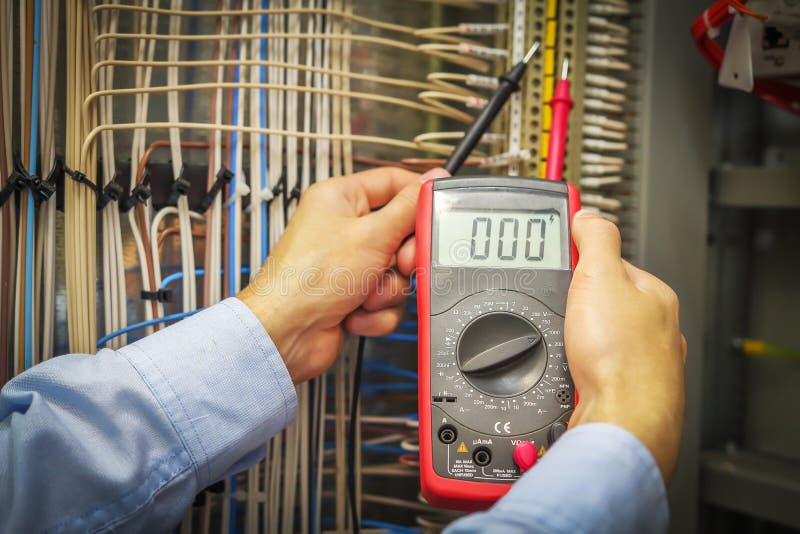 An electrician with multimeter close-up. Hands of service engineer with measuring instrument macro. royalty free stock photography
