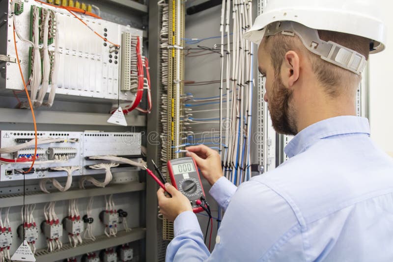 Electrician technician in fuse box. Maintenance engineer in control panel. Worker is testing automation equipment royalty free stock photo