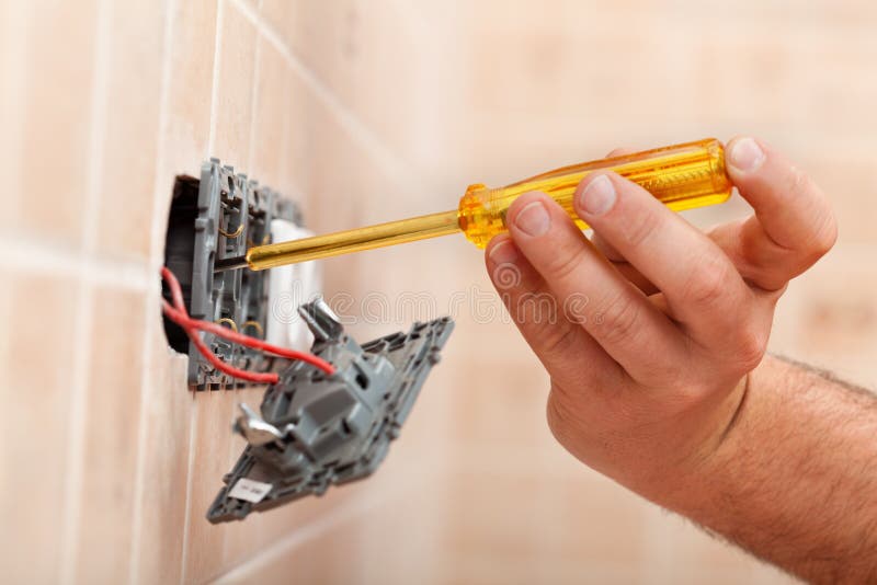 Electrician testing for electricity in electrical wall fixture