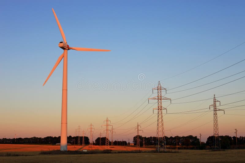 Electricity pylons and wind turbines against sky